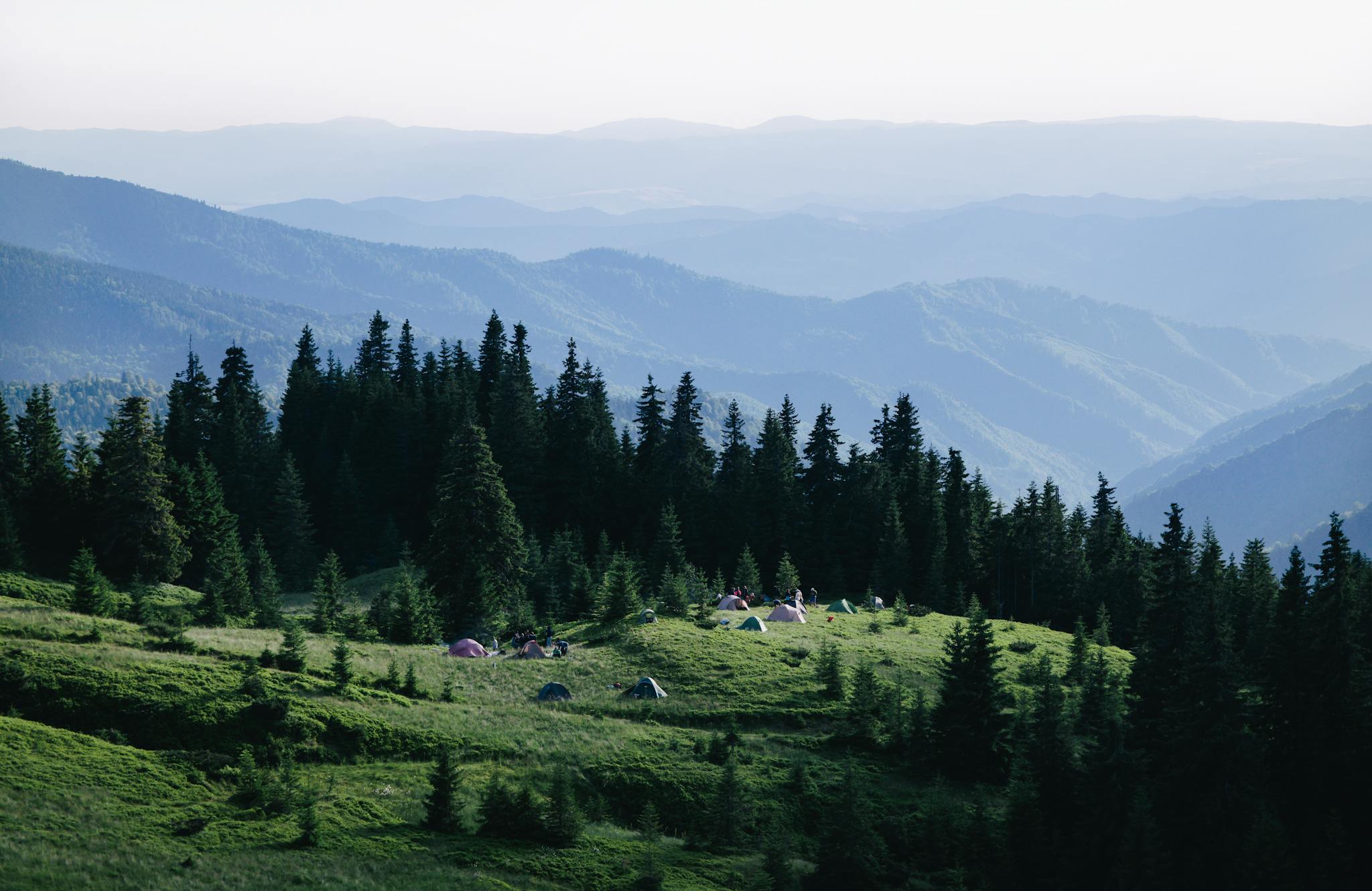 A picturesque view of a campsite in Holda, Romania surrounded by lush greenery and distant mountains.