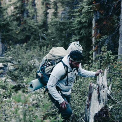 Outdoor adventurer hiking through lush forest in Canada with backpack.