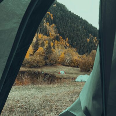 View from a tent of an autumn landscape with colorful trees and campsites.